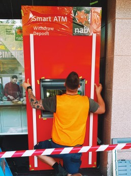 Man installing NAB branded ATM front cover to existing machinery.